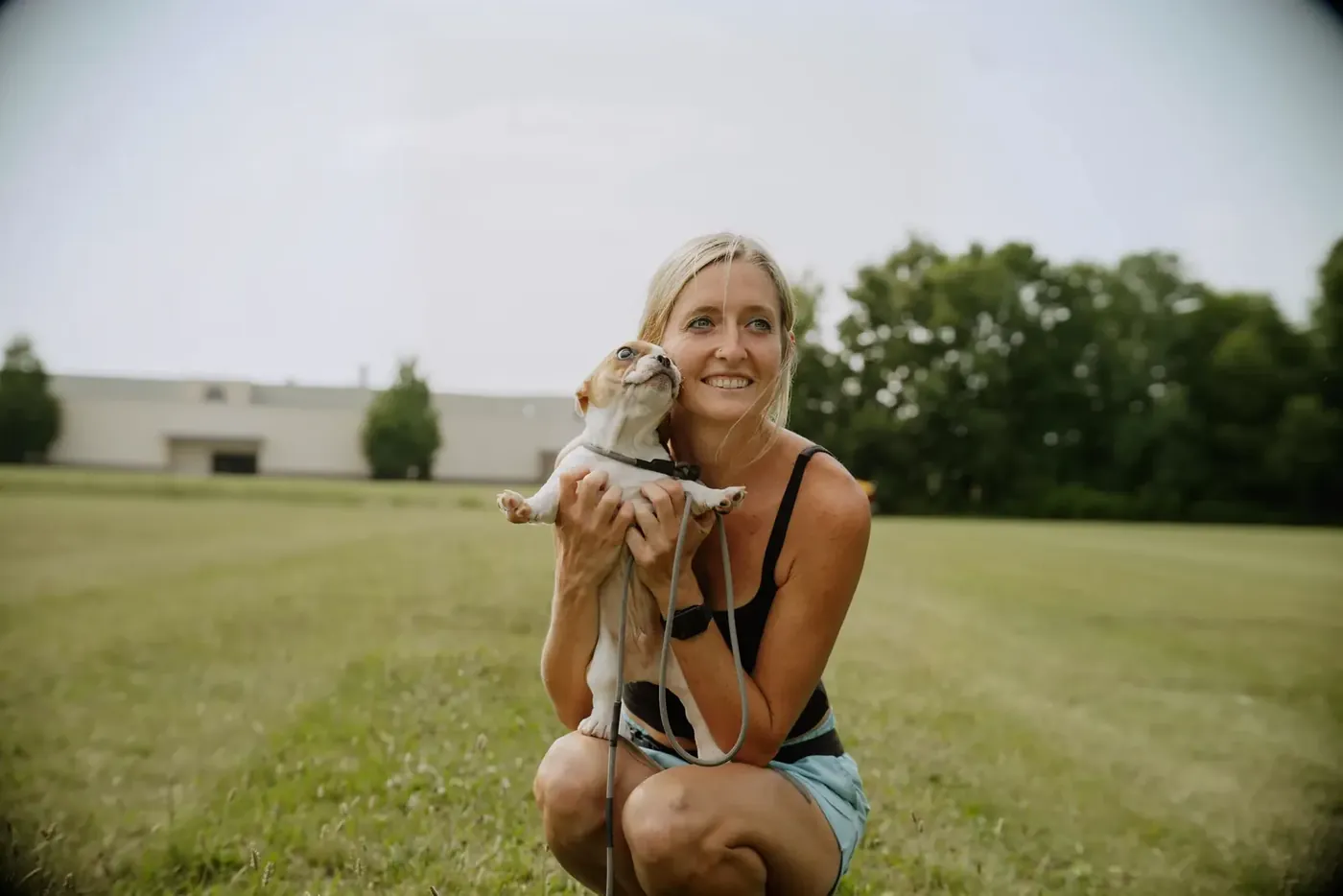 K9aholics trainer crouching with a puppy in her arms