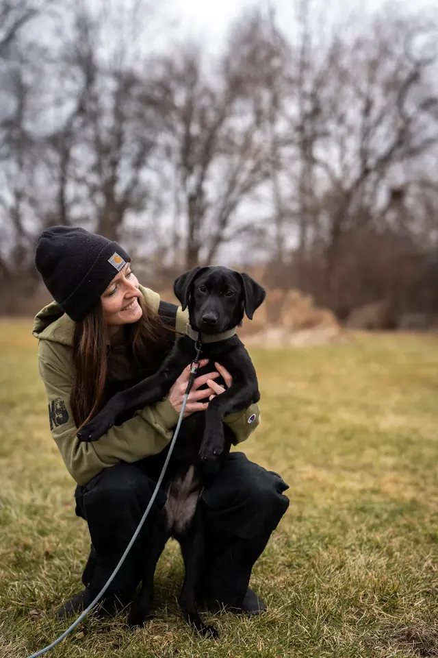 K9aholics trainer holding a black Lab puppy