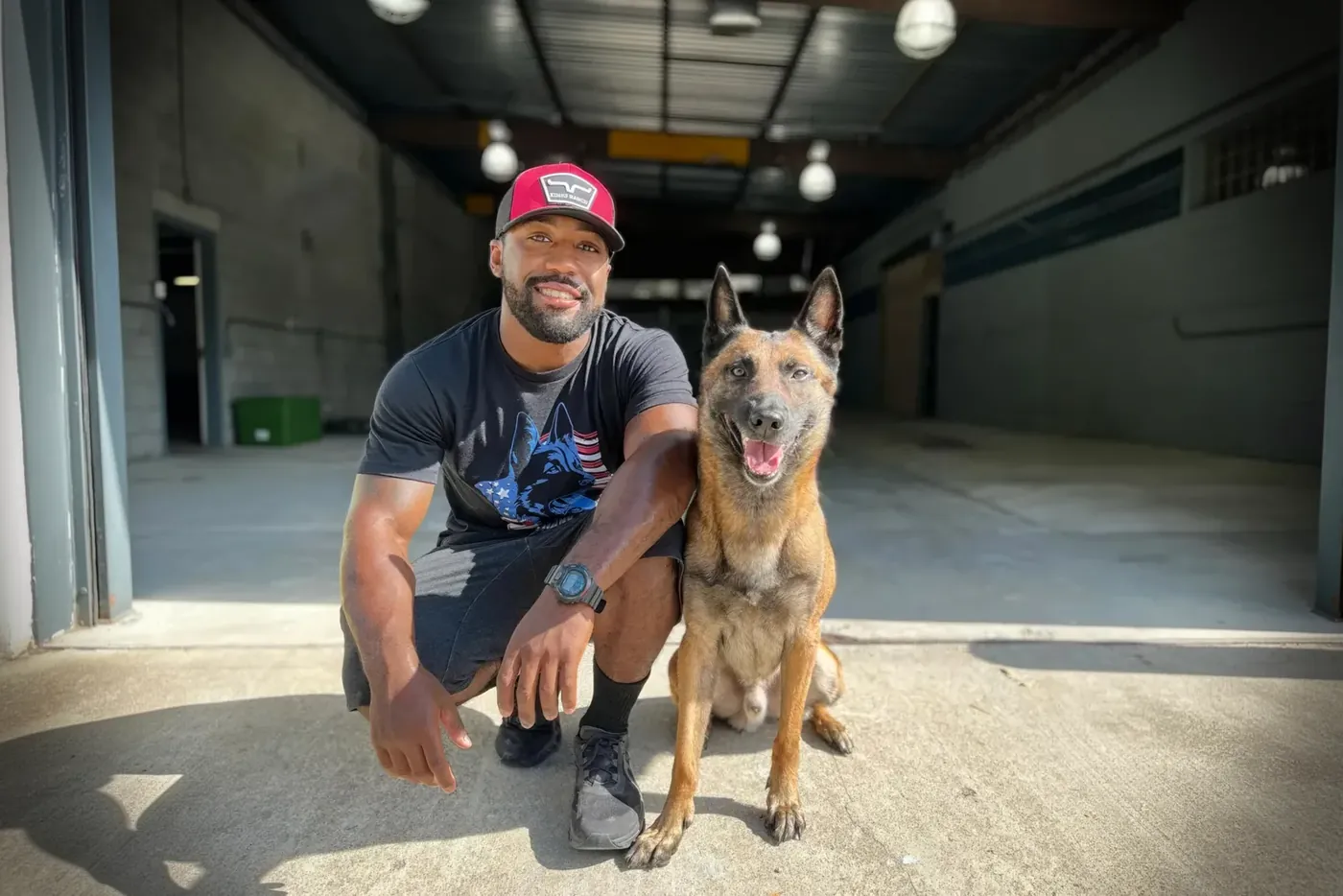 K9aholics trainer kneeling beside a Belgian Malinois