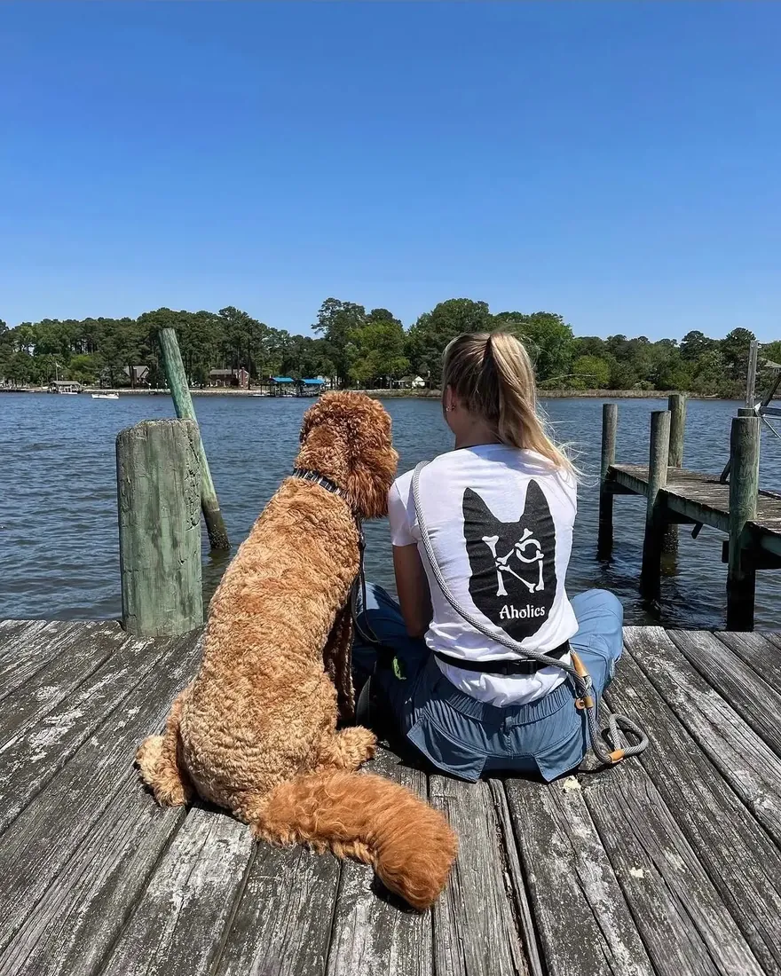 K9aholics trainer sitting on a dock beside a doodle